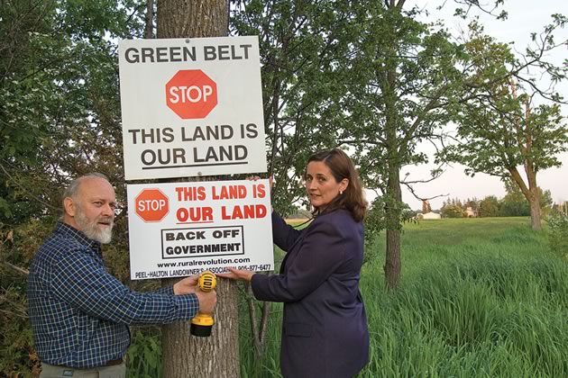 Ian Sinclair and Lynne Moore, both members of the Peel-Halton Landowners Association, erect one of the organization’s signs. The signs, with their bold message, have sprung up on farm fences around the countryside. Photo by Pete Paterson.