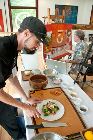 Owen Vulpe of What’s Cookin’ in Erin demonstrates the art of salad making in the Paul Morin Gallery, and Paul Morin paints on the right. Photo by Pete Paterson.