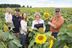 Sean and Amy Davis with baby Nora and Sean’s parents Joanne and John amid sunflowers they grow for birdseed at Davis Feed & Farm Supply. “2013 is the year I’ll never forget because we had four generations living on this farm,” says Sean. Photo by Pete Paterson.