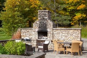A substantial outdoor fireplace is built into the dry-stone wall that encloses a vegetable garden and outdoor dining area. Photo by Pam Purves.