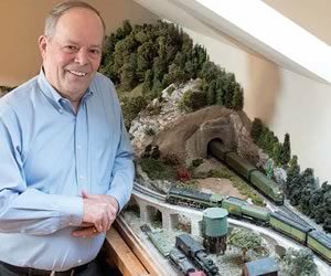Retired broadcast journalist Hap Parnaby in his third-floor train room. The tracks circle the room through an elaborate landscape he handcrafted. Photo by Pete Paterson.