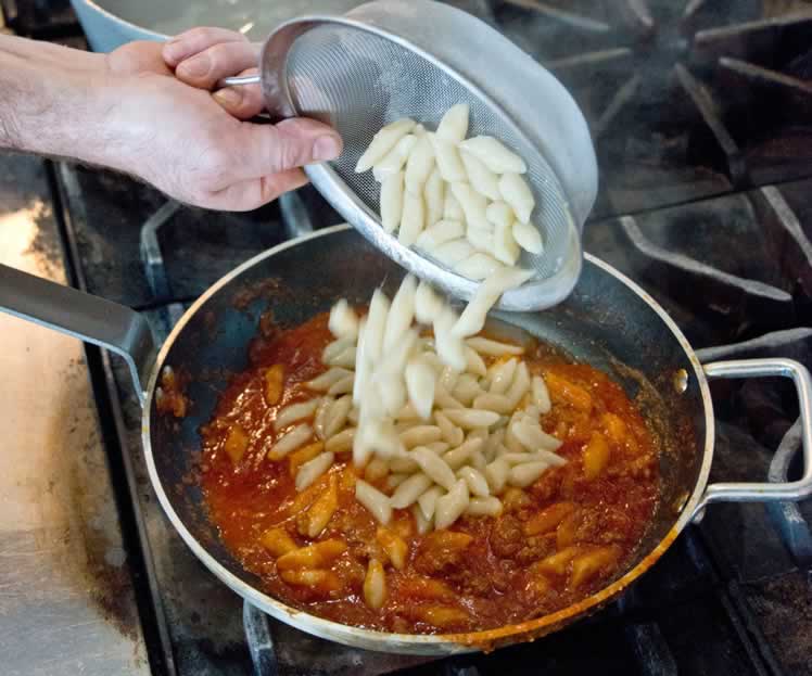 Either strain or use a strainer to scoop gnocchi from the water and directly into a pan with sauce. Stir the gnocchi into the sauce. Add grated Parmesan and stir once more before serving. Photo by Pete Paterson. Styling Jane Fellowes.
