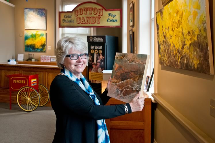Susan Reynolds holds a painting by Cathy Dalton, one of the artists in a recent show Susan curated in the lobby of Theatre Orangeville. Photo by Pete Paterson.
