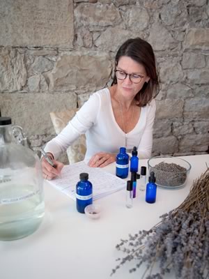 Lee Anne Downey sits at her kitchen counter with the lavender oil she pressed last summer at Stonewell Farm. She is developing ideas for a small-batch line of lavender products to debut this year. Photo by Rosemary Hasner / Black Dog Creative Arts.