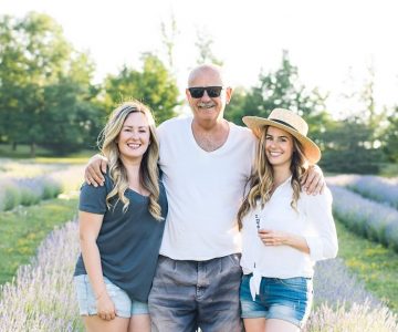 At their family farm near Creemore, Emma Greasley, left, and Jessica Ridding flank their father, Brian Greasley, between rows of lavender. Photo by Jessica Crandlemire, Light and Shadow Photography.