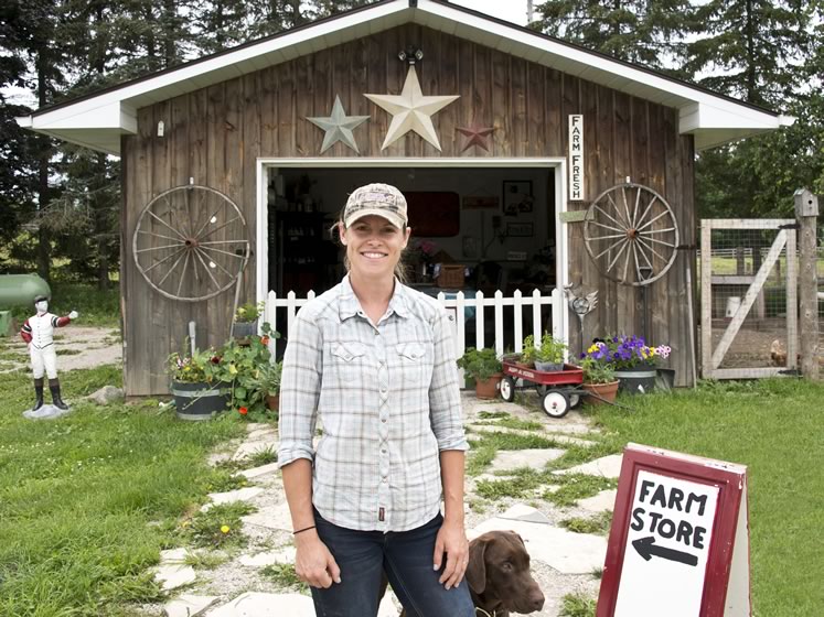 Rockcliffe Farm owner Alix Bezak in front of her on-farm shop with her chocolate lab, Goose. Photo by Pete Paterson.