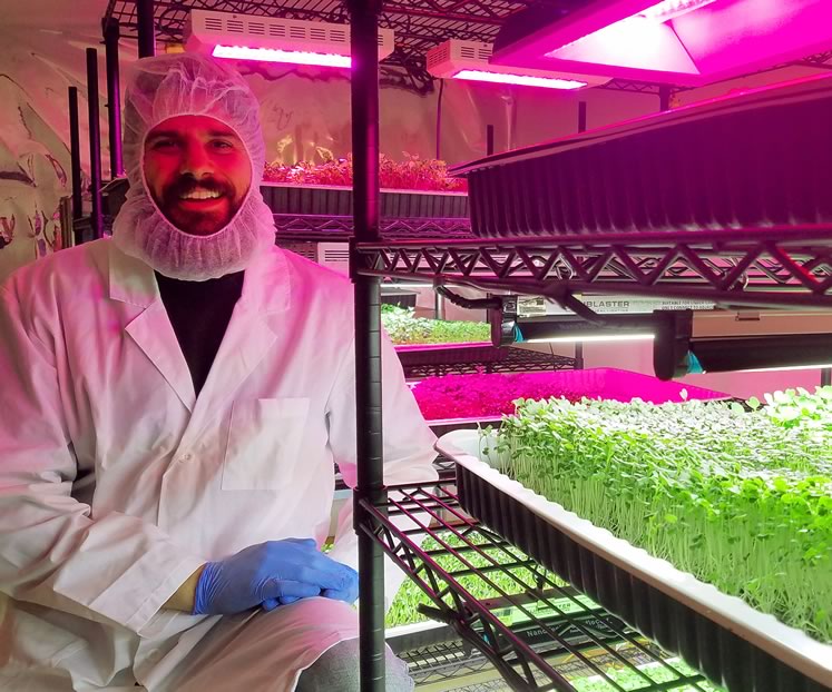Jonathan McCausland in the grow area of Mansfield’s Big Thunder Farms with a brassica blend microgreens crop. Photo by Joseph McCausland.