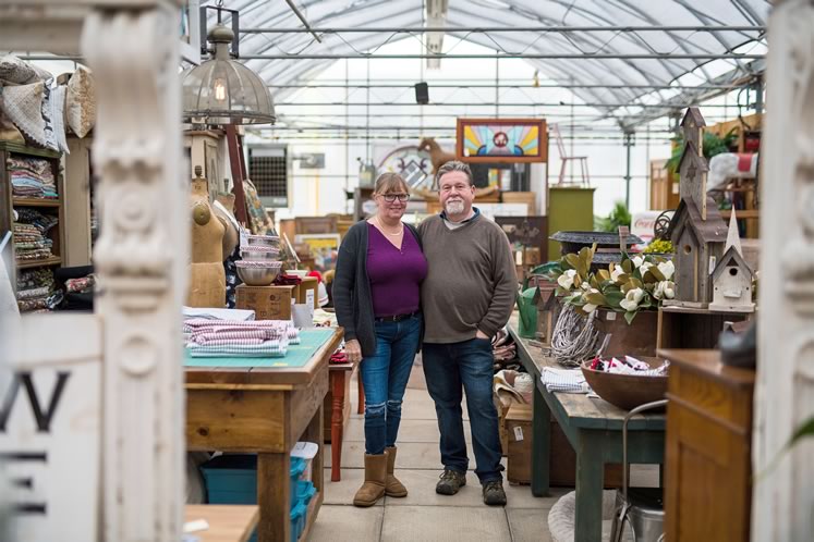 Joanne and Martin Woudenberg stand next to her sewing station amid the store’s carefully curated antiques. Photo by James MacDonald.