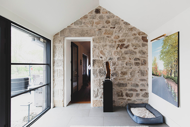 A glassed-in breezeway now serves as the main entrance to the home. A doorway to the living area was carefully cut through the former exterior wall. The citrine geode is from Brazil and the painting Road in Caledon is by Kenneth M. Kirsch. Photo by Erin Fitzgibbon.