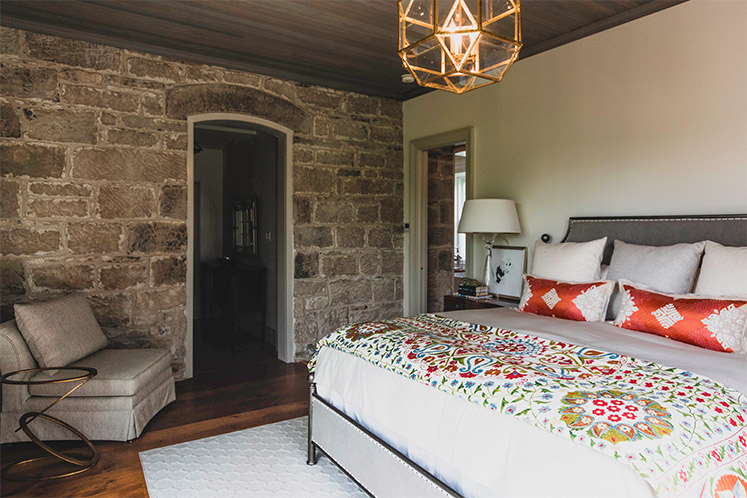 Lee Anne and Tom’s new bedroom was built on the main floor off the dining area and features another formerly exterior stone wall. Photo by Erin Fitzgibbon.
