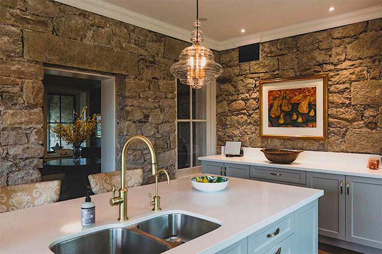 When she renovated the kitchen, Lee Anne decided against upper cabinets in favour of showcasing the thick original stone walls. Photo by Erin Fitzgibbon.