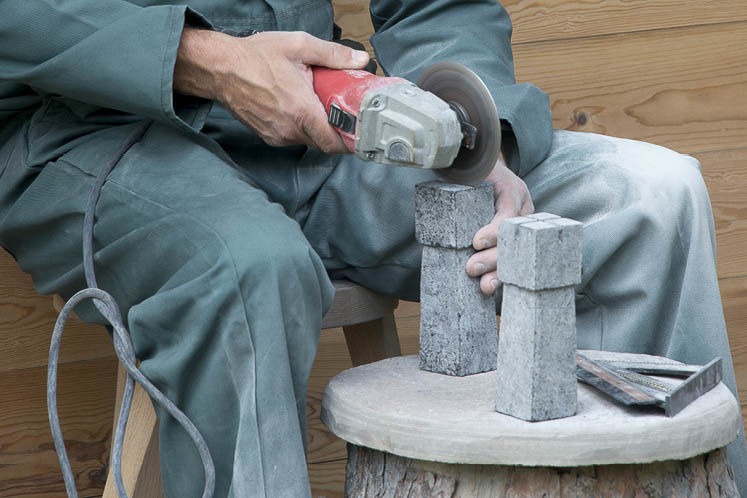 Colby uses tools including a diamond blade and a grinder to craft individual chess pieces.